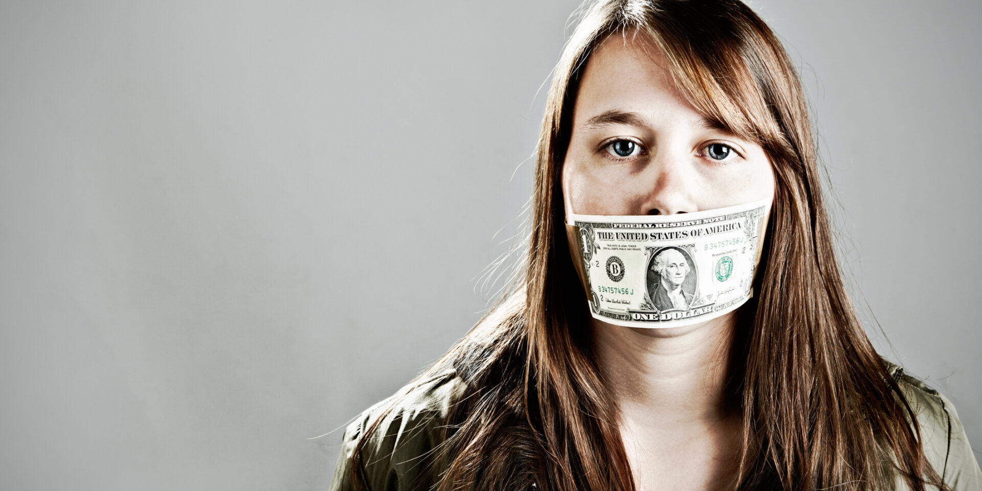 This young woman seems to have accepted being gagged with a US one dollar bill; she'll keep quiet if she's paid to!